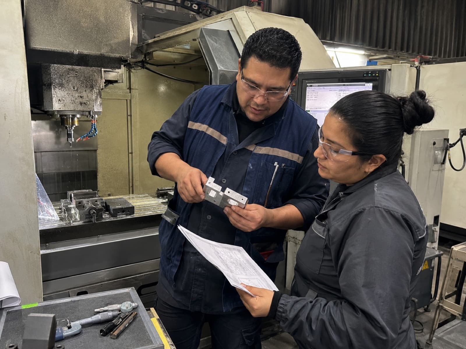 Engineers inspecting a machined part against its drawing